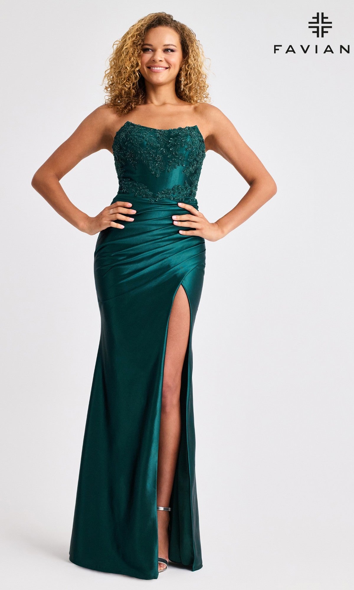 A woman poses against a white background in the Faviana 11429 long prom dress, featuring a sleeveless emerald green design with a beaded bodice and high slit. The Faviana logo appears in the top right corner.
